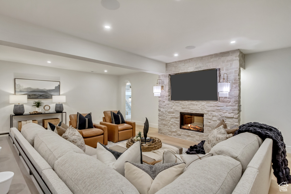 Living room with recessed lighting, a fireplace, arched walkways, and wood finished floors