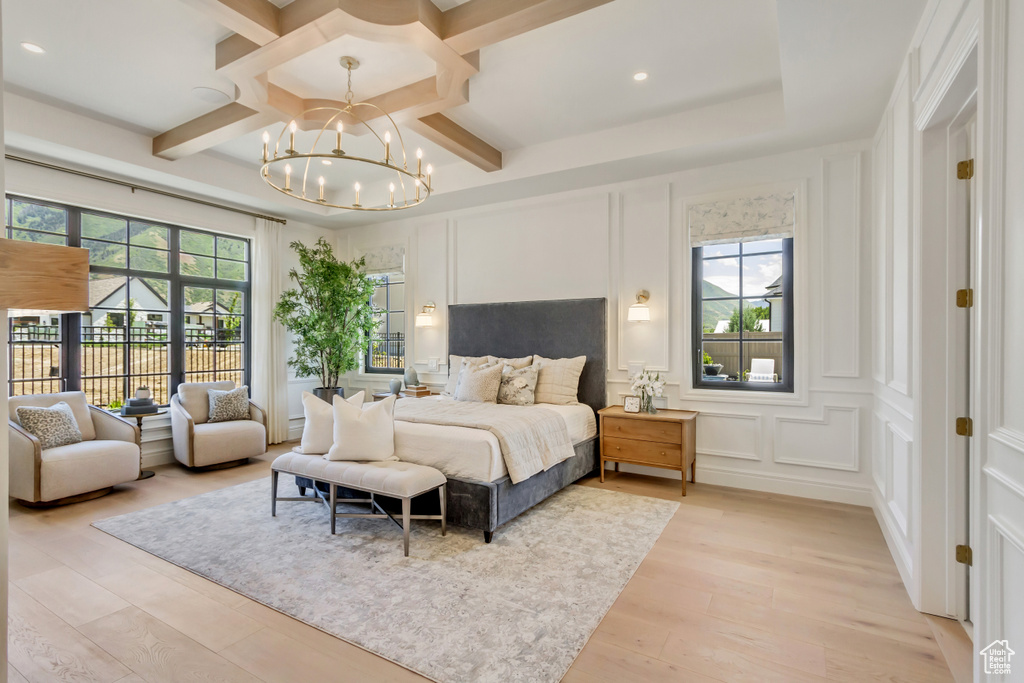 Bedroom with a decorative wall, coffered ceiling, a chandelier, light wood-style flooring, and beam ceiling