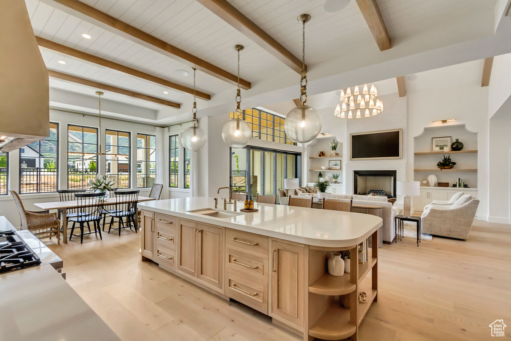 Kitchen with light brown cabinets, a sink, open shelves, light wood-type flooring, and beam ceiling
