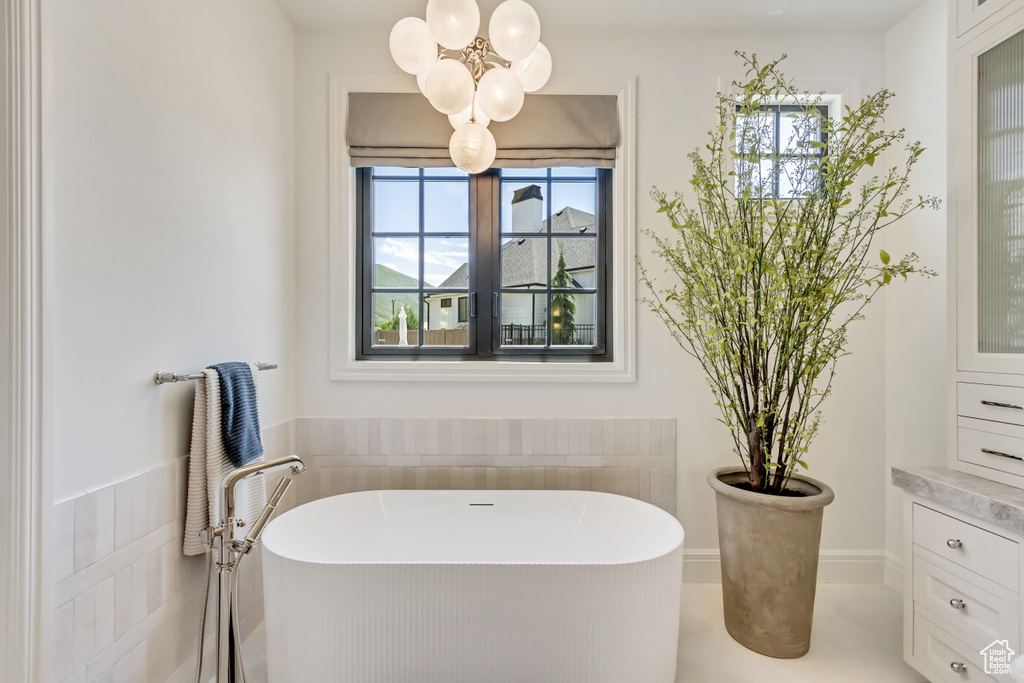 Bathroom with a soaking tub, plenty of natural light, and a chandelier