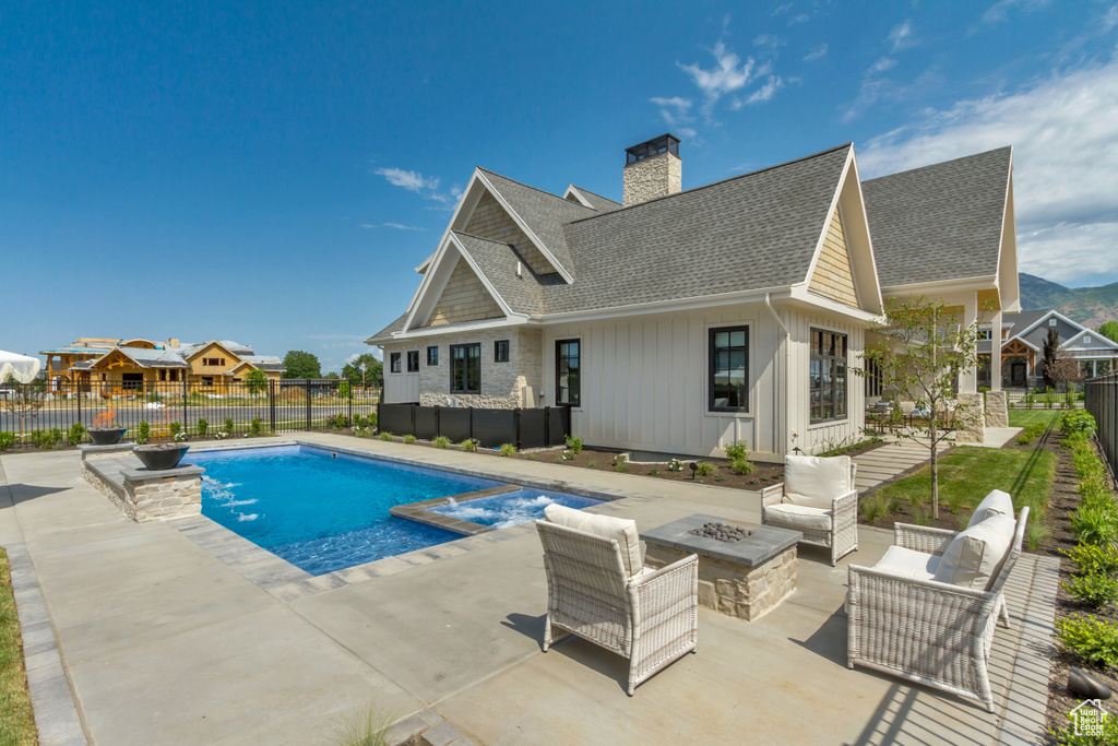 View of pool featuring an outdoor living space with a fire pit, a patio area, a fenced backyard, and a pool with connected hot tub