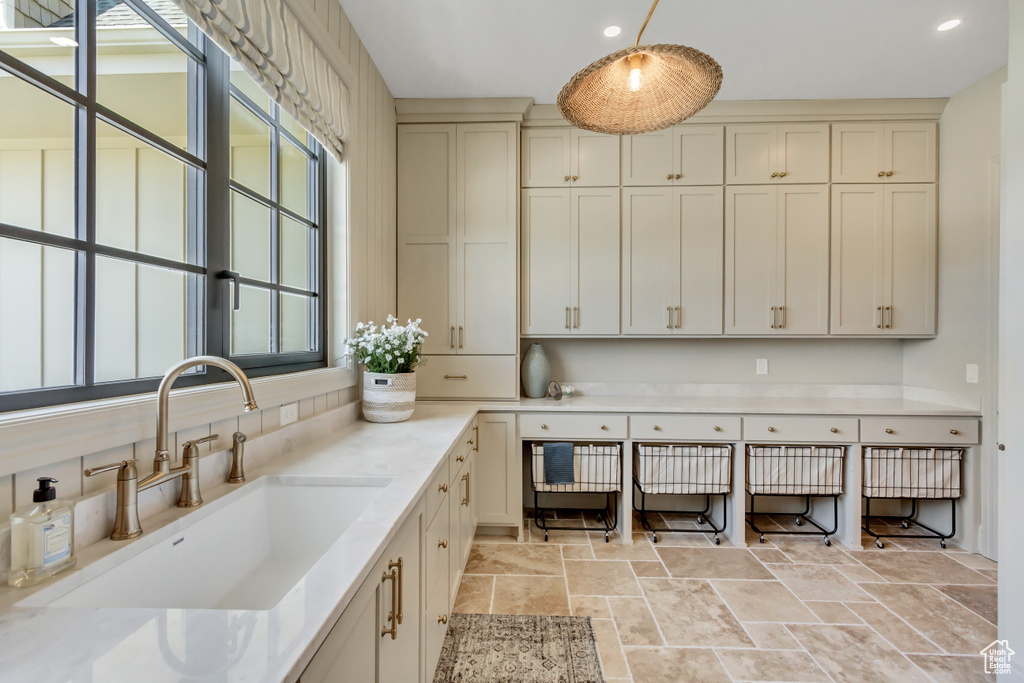 Kitchen featuring stone tile floors, light countertops, recessed lighting, pendant lighting, and cream cabinets