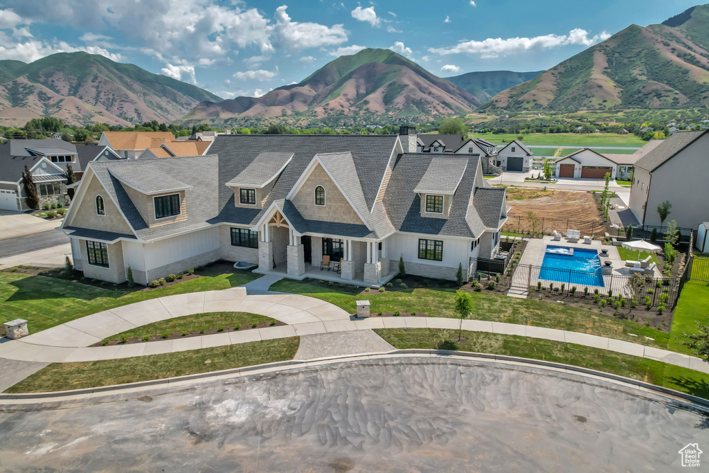 View of front of home with a porch, a mountain view, a shingled roof, and a residential view