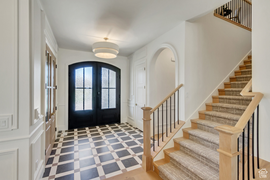 Entrance foyer with a decorative wall, french doors, stairs, and arched walkways