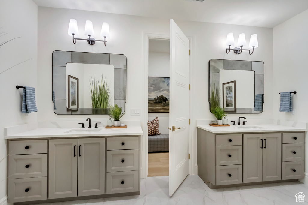 Full bath featuring marble finish floors and two vanities