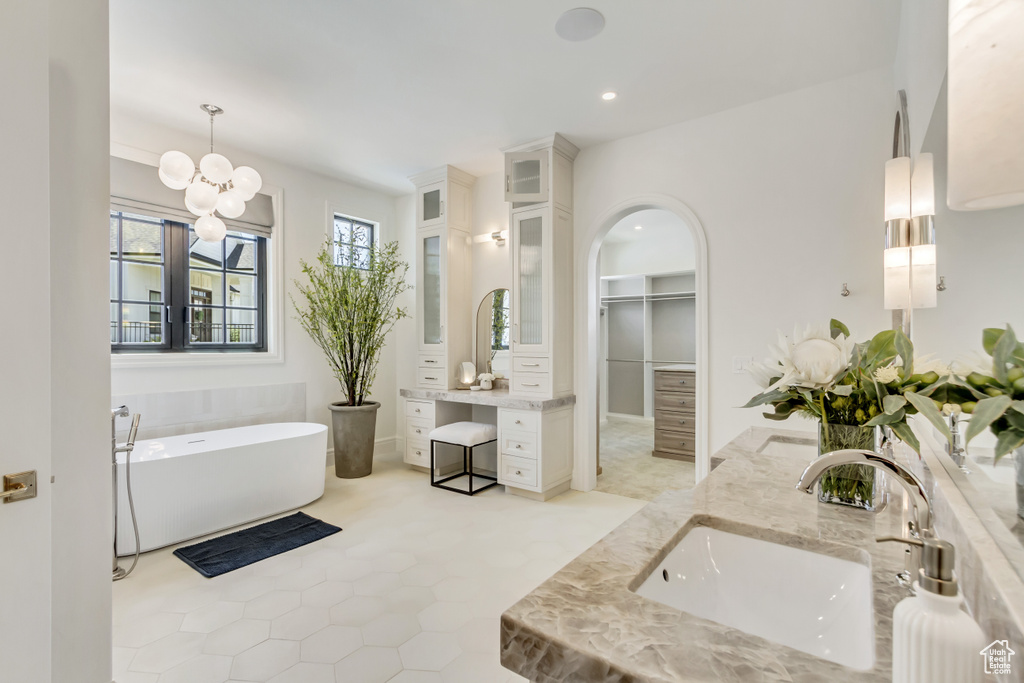 Bathroom with double vanity, a soaking tub, recessed lighting, a chandelier, and a walk in closet