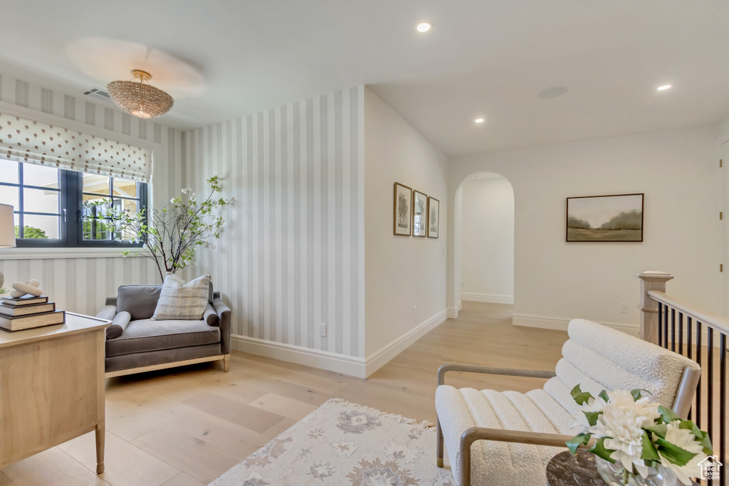 Living area featuring light wood-style floors, arched walkways, wallpapered walls, and recessed lighting