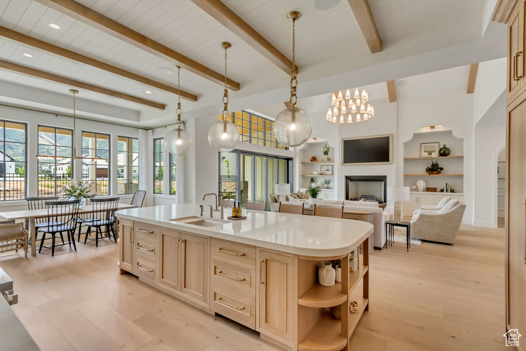 Kitchen with a sink, light brown cabinets, open shelves, light countertops, and light wood-type flooring