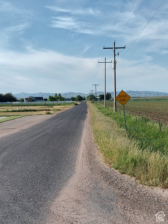 View of asphalt road with a view of countryside, a mountain view, and traffic signs