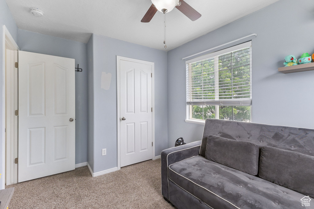 Sitting room featuring a ceiling fan, carpet flooring, and baseboards