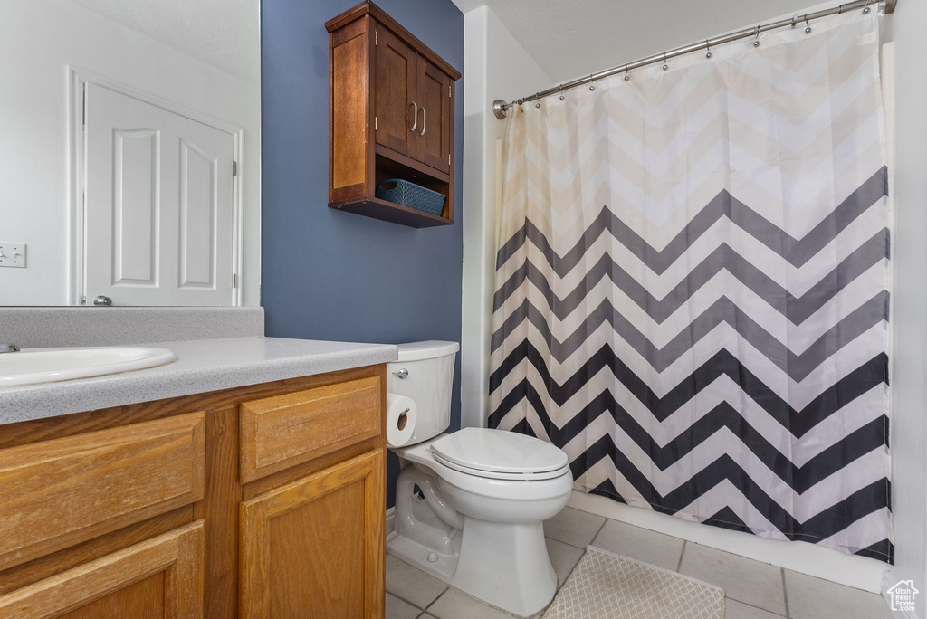 Full bathroom featuring vanity, tile patterned floors, toilet, and a shower with curtain