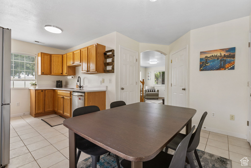 Dining room featuring light tile patterned floors, arched walkways, baseboards, and plenty of natural light