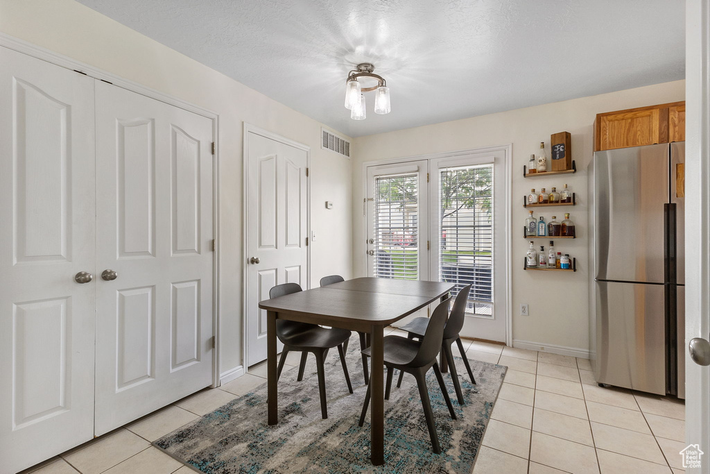 Dining space featuring light tile patterned flooring, a bar, and baseboards