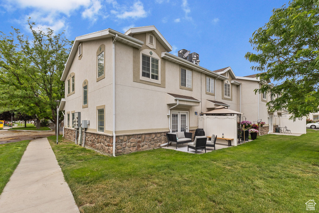Rear view of property featuring outdoor lounge area, a gazebo, stucco siding, and a lawn