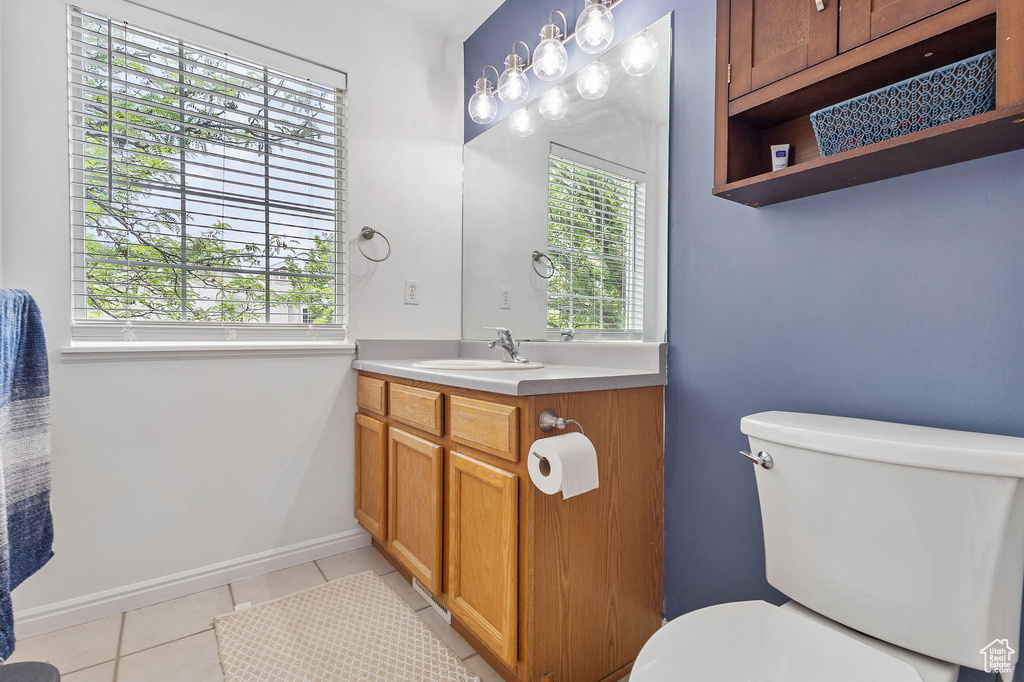 Bathroom with tile patterned floors, vanity, toilet, and plenty of natural light