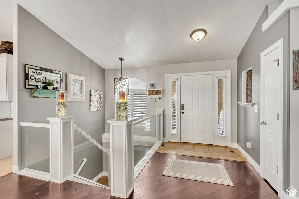 Entryway with wood finished floors, vaulted ceiling, and baseboards