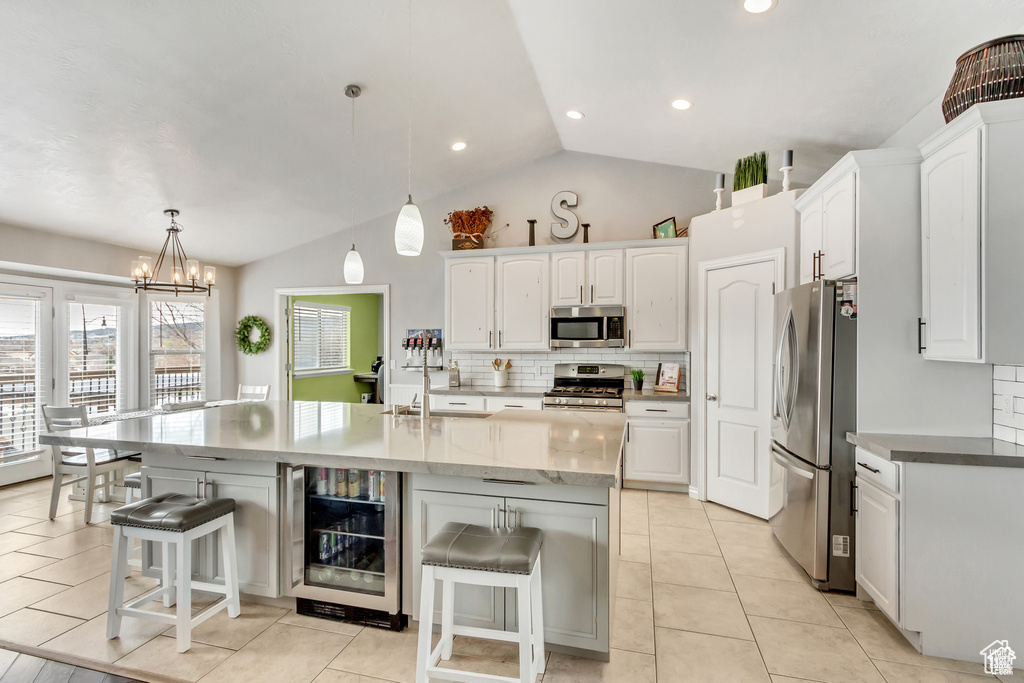 Kitchen with stainless steel appliances, beverage cooler, a breakfast bar area, white cabinets, and tasteful backsplash
