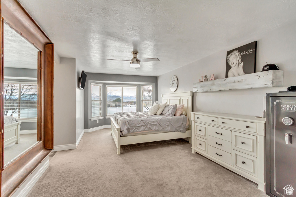 Bedroom featuring light colored carpet, a textured ceiling, ceiling fan, and baseboards