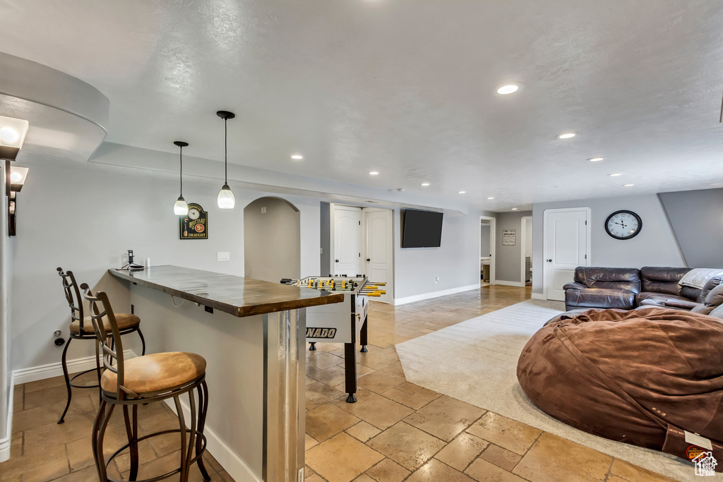 Kitchen with a kitchen breakfast bar, baseboards, recessed lighting, arched walkways, and butcher block countertops
