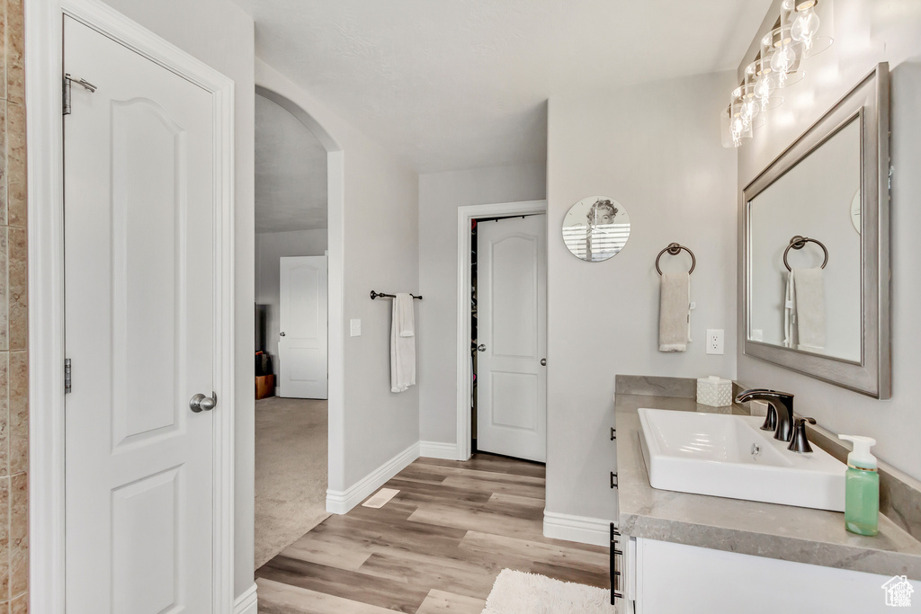 Bathroom with vanity, wood finished floors, and baseboards