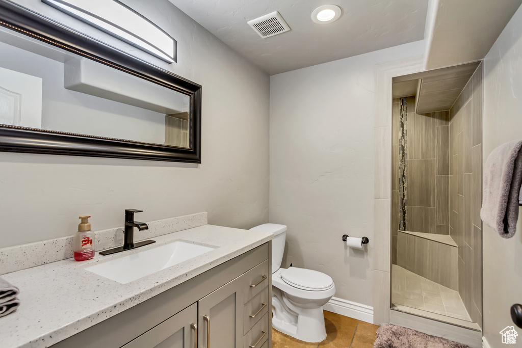 Bathroom with a shower stall, vanity, toilet, and tile patterned flooring