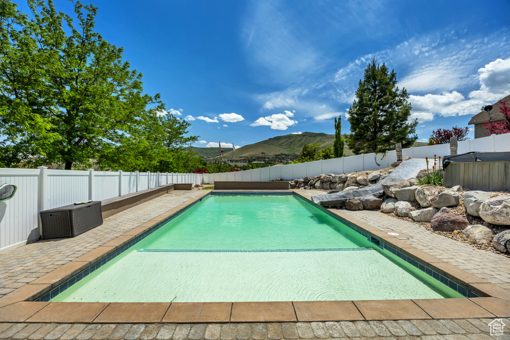 View of swimming pool featuring a fenced backyard, a patio, a mountain view, and a hot tub
