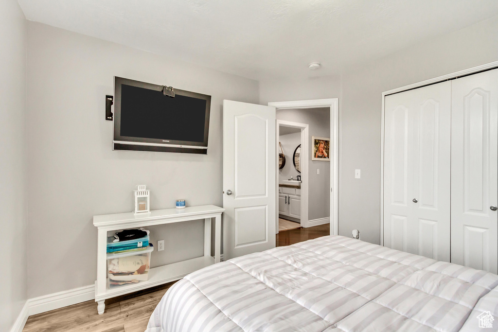 Bedroom with wood finished floors, baseboards, and a closet