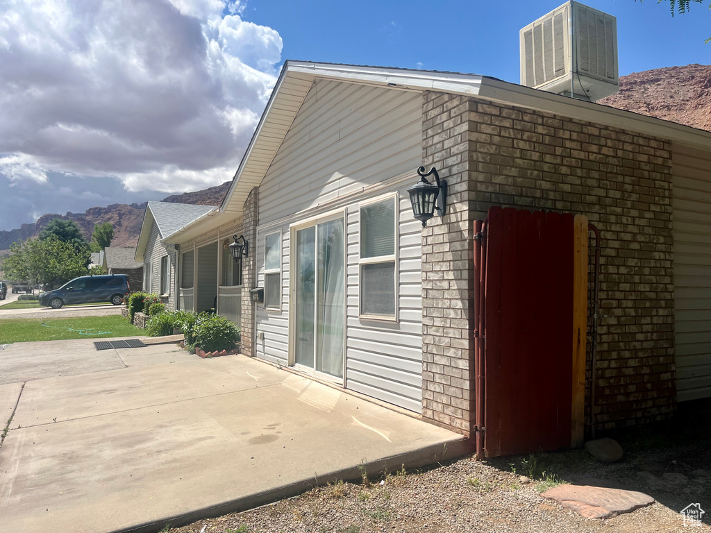 View of property exterior featuring central AC, a patio area, a mountain view, and brick siding