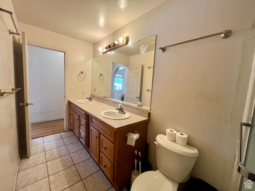 Full bath featuring double vanity, toilet, and tile patterned flooring