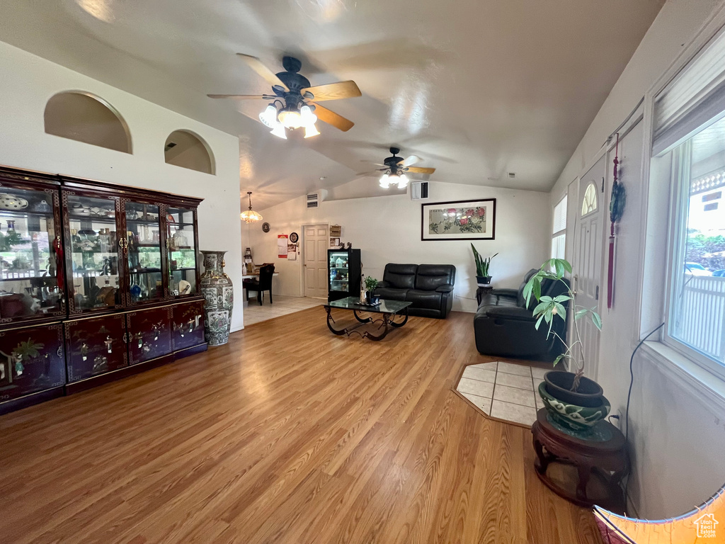 Living room with vaulted ceiling, wood finished floors, a ceiling fan, and healthy amount of natural light