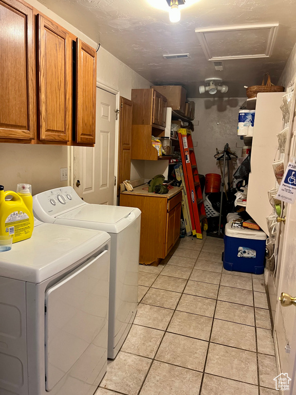 Laundry room with cabinet space, washer and clothes dryer, attic access, and light tile patterned floors