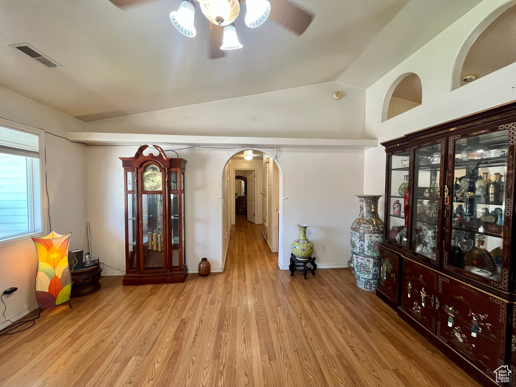 Empty room featuring ceiling fan, arched walkways, vaulted ceiling, and wood finished floors