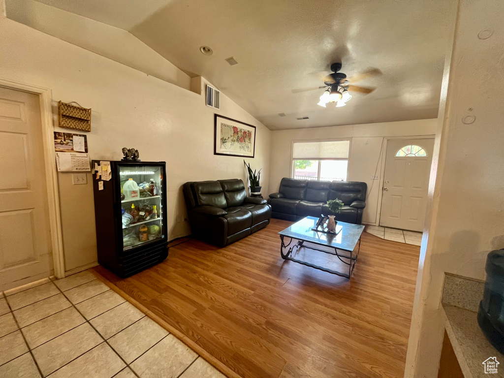 Living area with lofted ceiling, a ceiling fan, and light wood finished floors