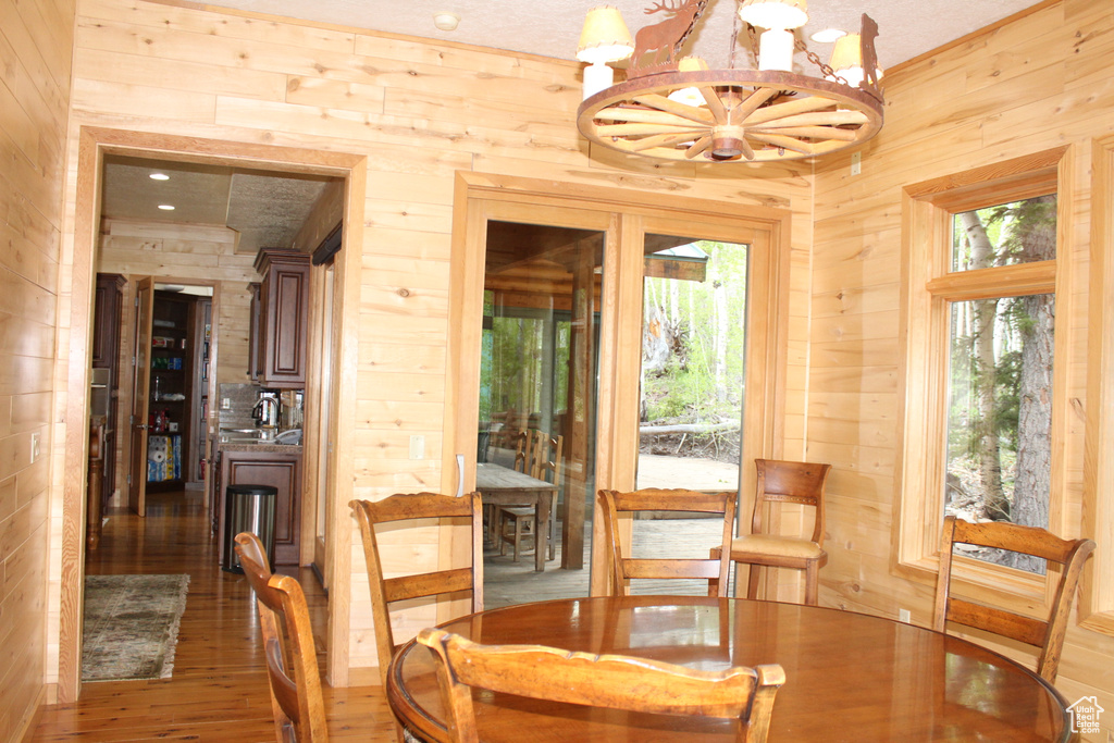 Dining space featuring wood walls, a chandelier, and wood finished floors