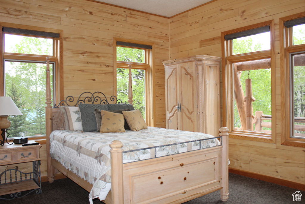 Bedroom featuring wood walls and dark colored carpet