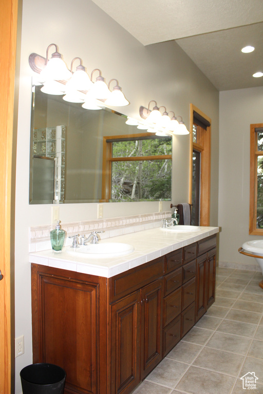 Full bathroom featuring double vanity, tile patterned floors, decorative backsplash, and recessed lighting