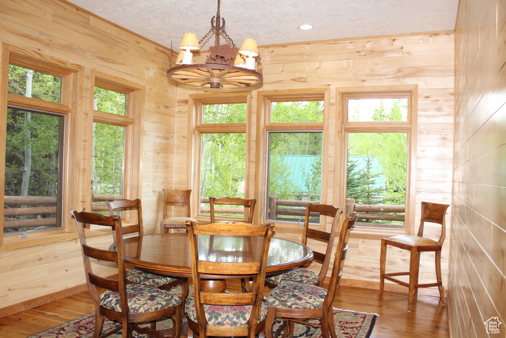Dining area featuring wooden walls, a chandelier, and hardwood / wood-style floors
