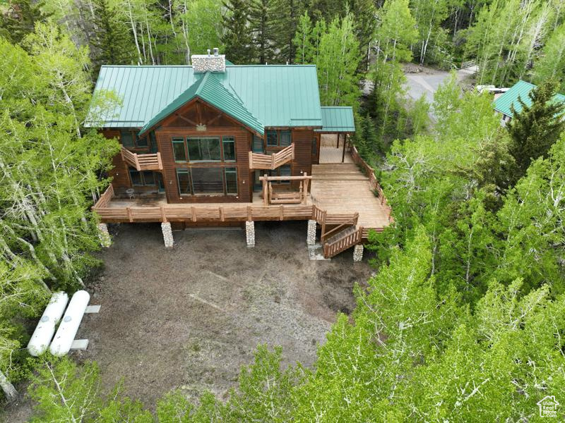 Rear view of house with a chimney, a standing seam roof, a wooden deck, and metal roof
