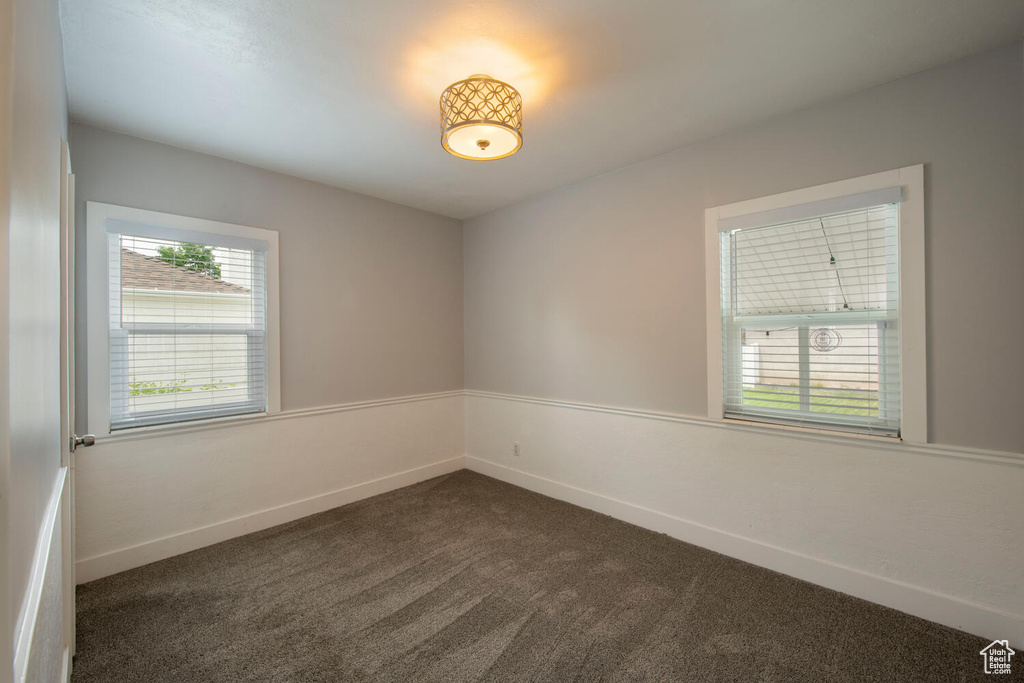 Empty room with dark carpet and baseboards