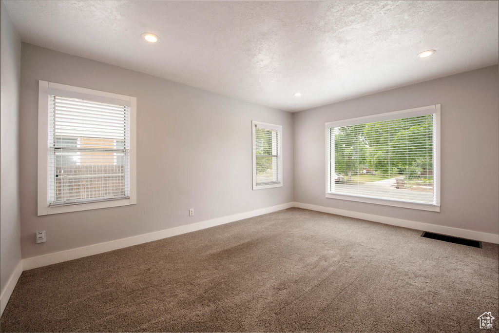 Carpeted empty room with baseboards, a textured ceiling, and recessed lighting
