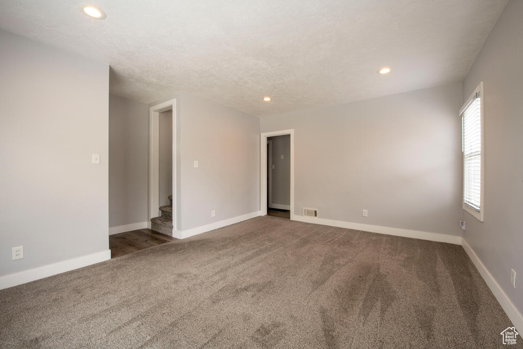 Carpeted empty room with stairs, recessed lighting, and baseboards