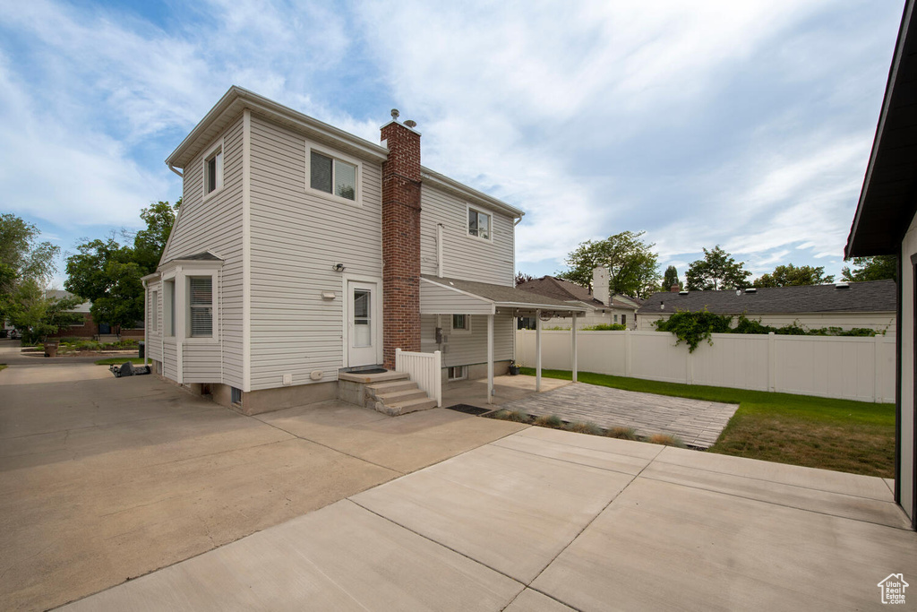 Rear view of property featuring a chimney and a patio area