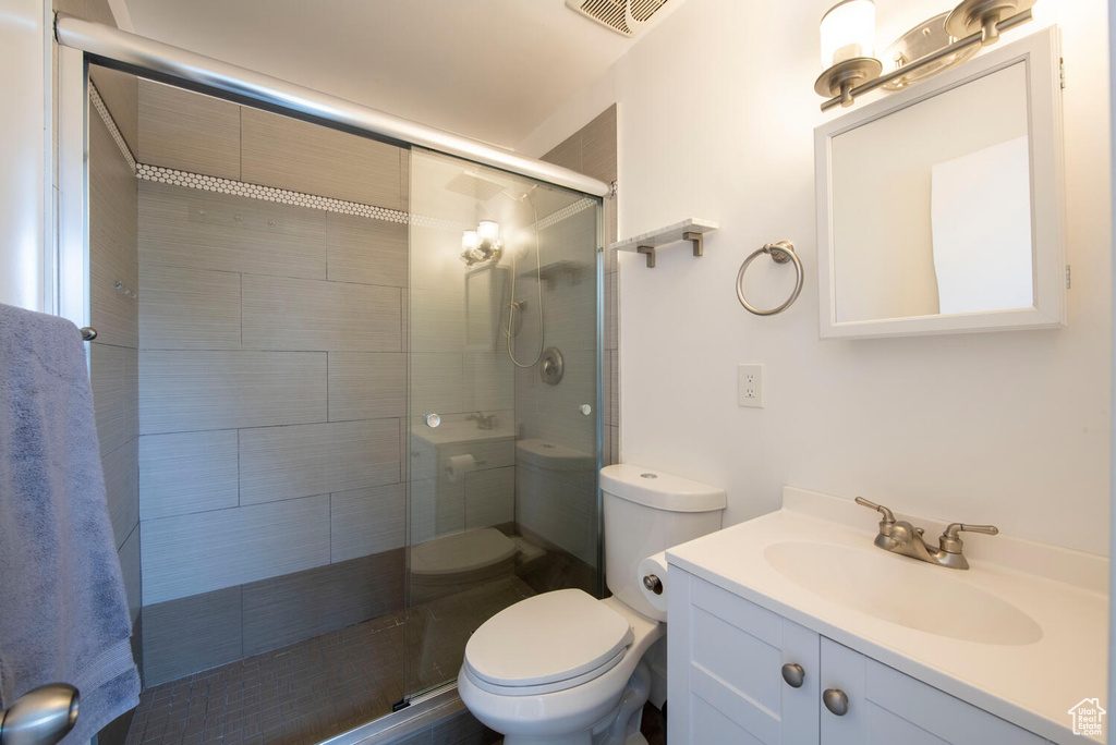 Full bath with toilet, a tile shower, and vanity