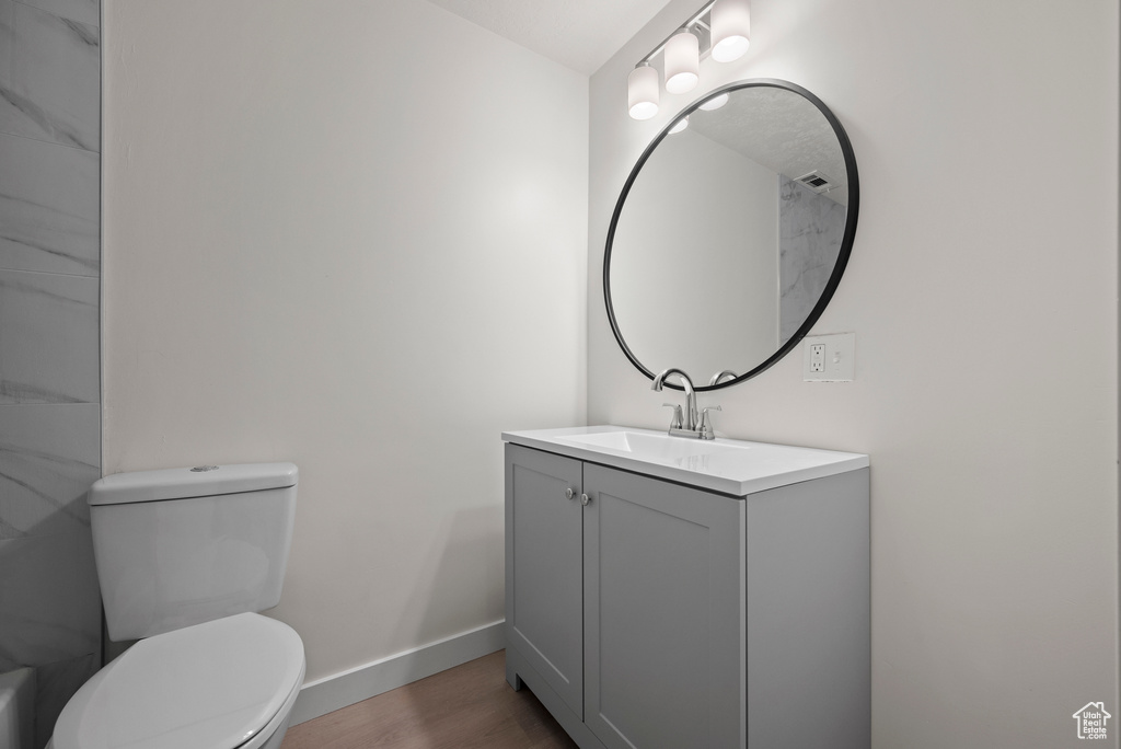Bathroom with vanity, baseboards, toilet, and wood finished floors