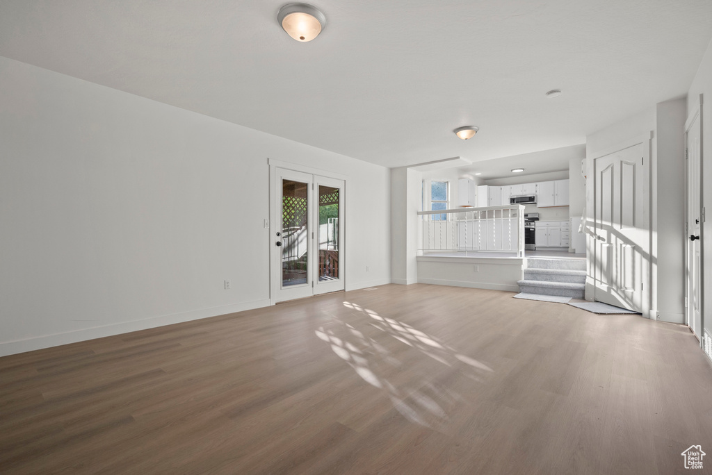 Unfurnished living room featuring wood finished floors and baseboards