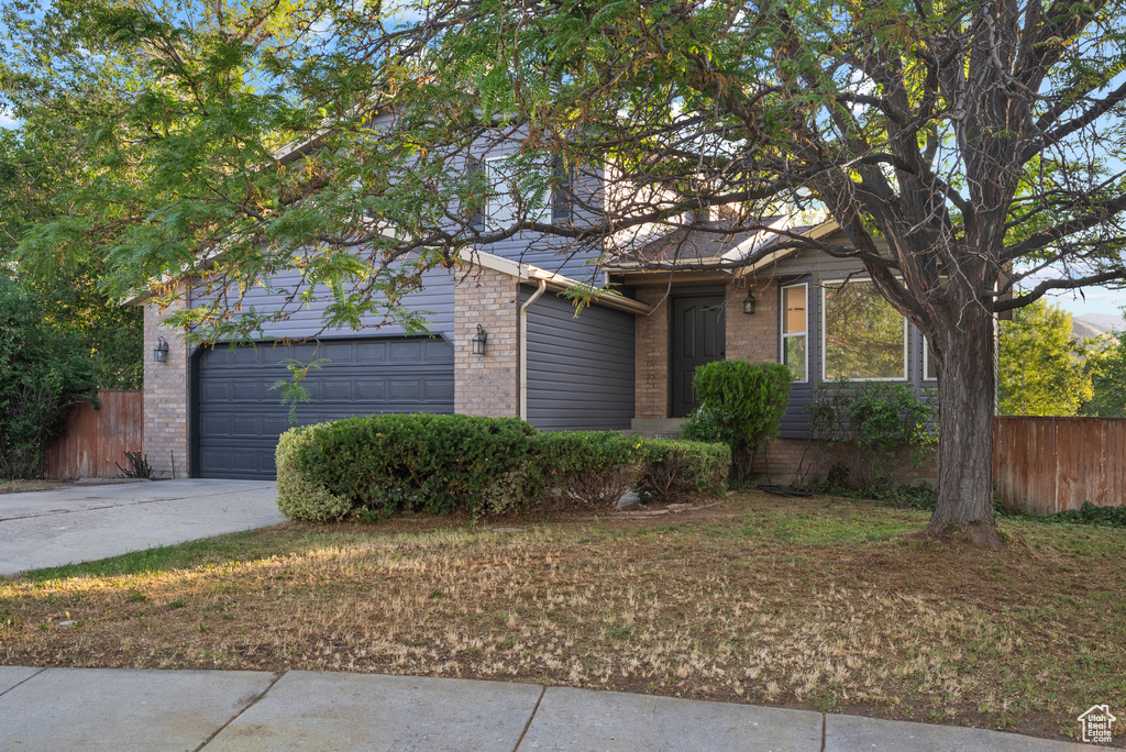 View of front of home with brick siding, a garage, and concrete driveway