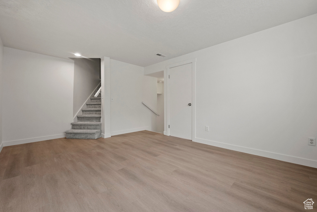 Basement with light wood finished floors, stairway, and baseboards