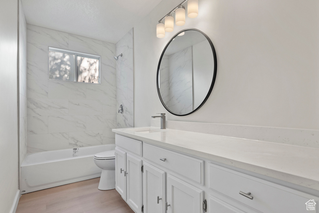 Bathroom with vanity, toilet,  shower combination, and wood finished floors