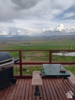 Wooden terrace featuring area for grilling and a water view