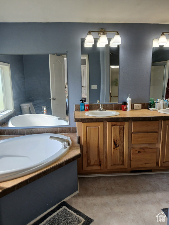 Full bath with double vanity, a garden tub, a shower with shower door, and tile patterned floors